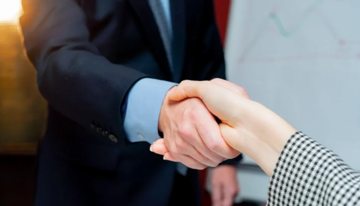 Two business people shaking hands representing the cost of commission errors between agents and BGAs or Carriers.