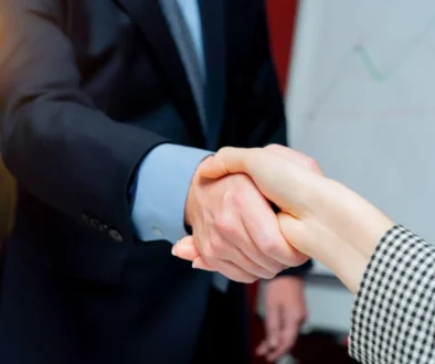 Two business people shaking hands representing the cost of commission errors between agents and BGAs or Carriers.