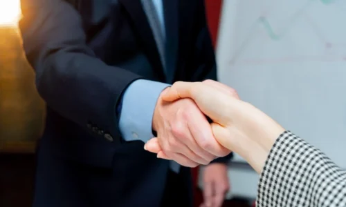 Two business people shaking hands representing the cost of commission errors between agents and BGAs or Carriers.